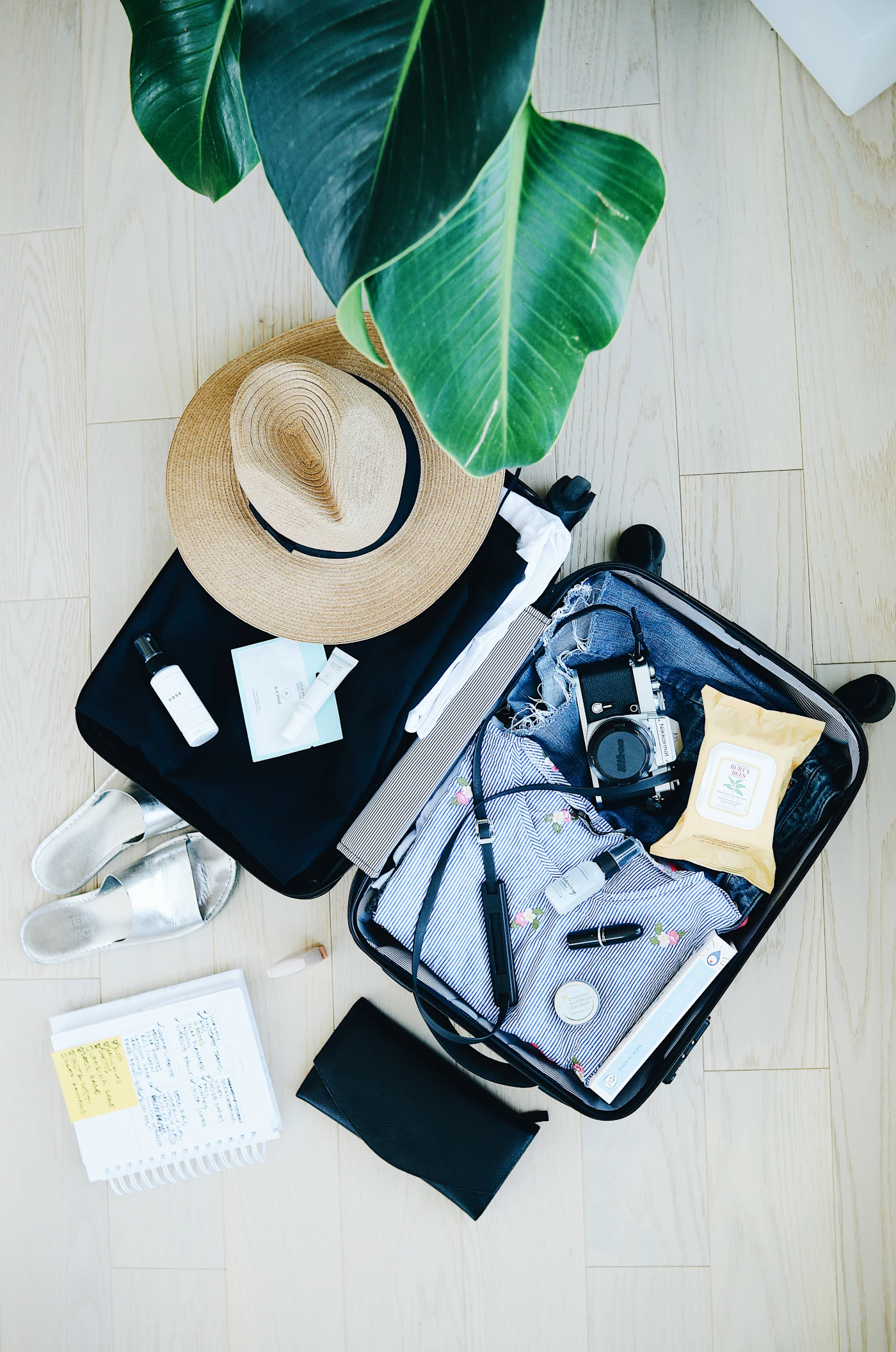 Open suitcase packed with clothes beside a written packing list